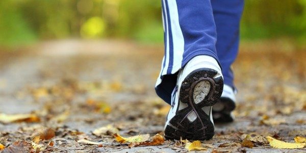 Pies caminando por un sendero con hojas caídas, simbolizando un estilo de vida saludable Feet walking on a path with fallen leaves, symbolizing a healthy lifestyle
